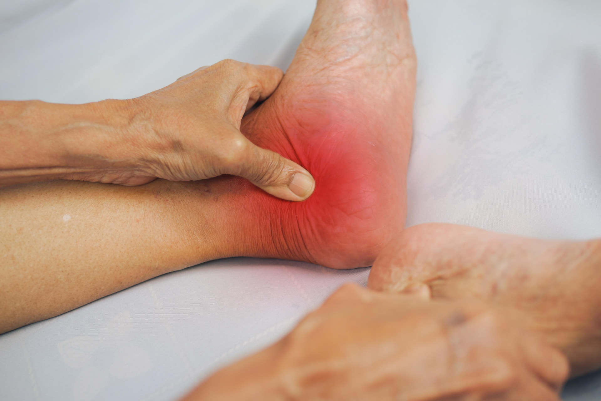 A person holding their foot, with arthritic pain highlighted at the ankle joint