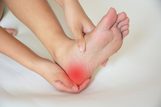 Illustration of heel pain — a foot being examined with pain highlighted at the heel