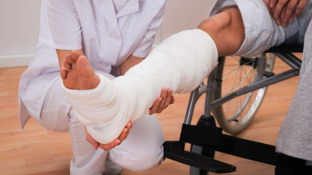 A therapist supporting a leg in a cast during rehabilitation after a road traffic accident
